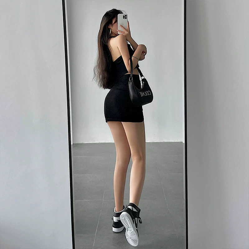 Bộ trang phục gồm áo crop top ôm sát cổ halter và chân váy xếp ly ôm sát eo cao dành cho nữ.