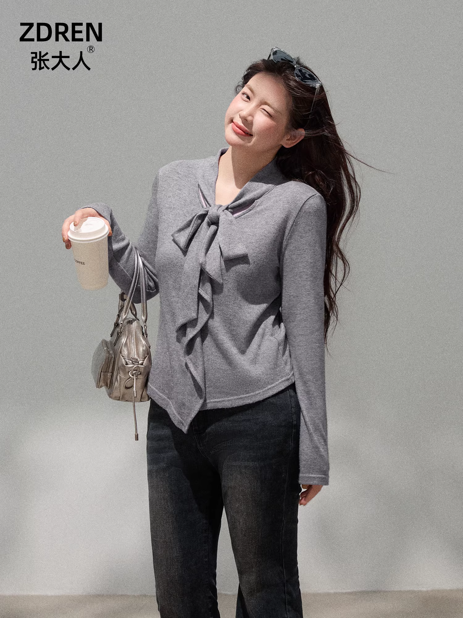 Bộ quần áo nữ cỡ lớn dành cho người lớn, gồm áo kiểu dáng độc đáo màu xám nhạt có nơ và quần jean ống rộng lưng cao.