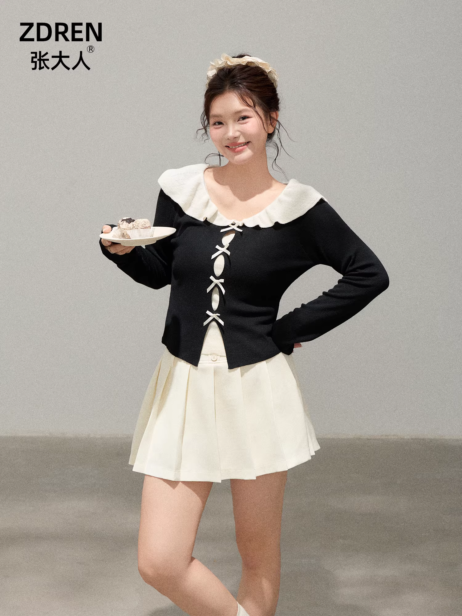 Quần áo nữ cỡ lớn dành cho người lớn, bộ hai mảnh giúp thon gọn dáng người cho các cô gái mũm mĩm, áo cổ búp bê kiểu Pháp, chân váy xếp ly màu trắng.