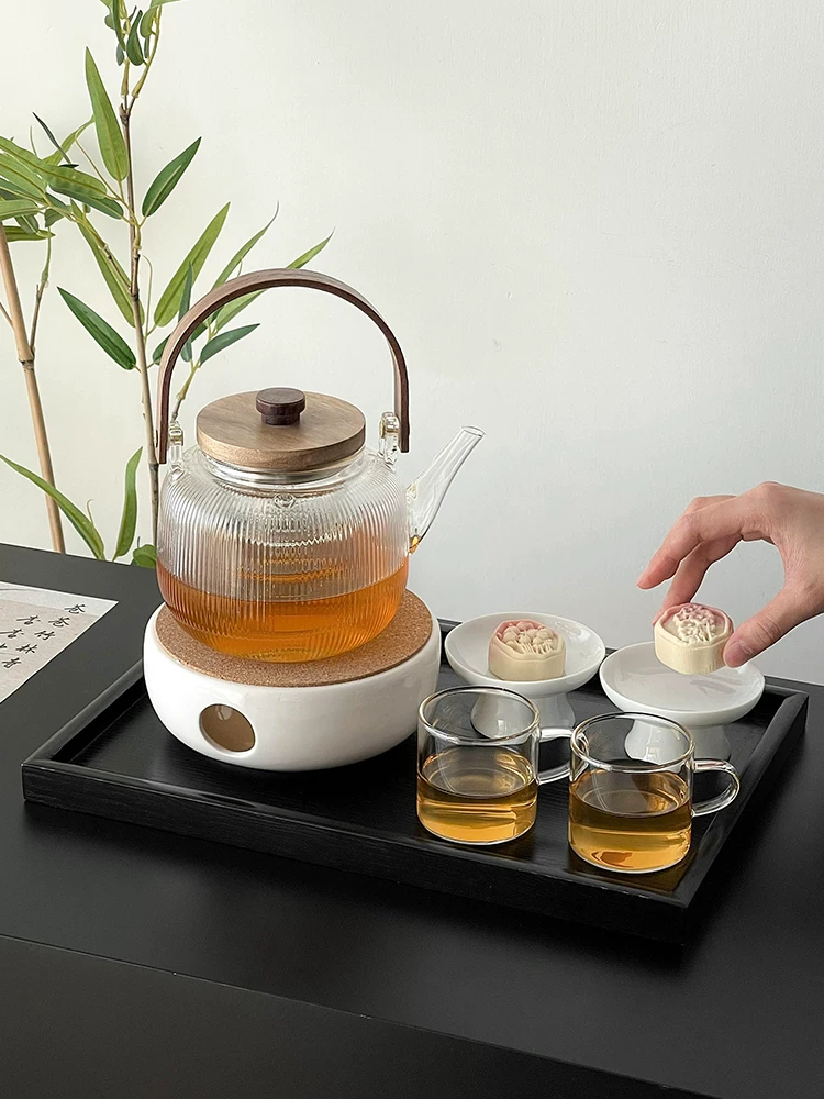 Bộ dụng cụ pha trà với ấm trà bằng thủy tinh chịu nhiệt cao, chén trà và bếp trà bằng gốm.