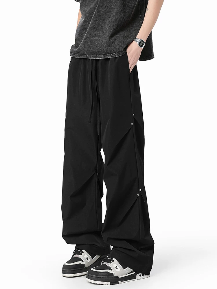 Quần dù xếp ly đính đinh tán Jeanswest dành cho nam, quần ống rộng dáng suông phong cách Mỹ mùa xuân.