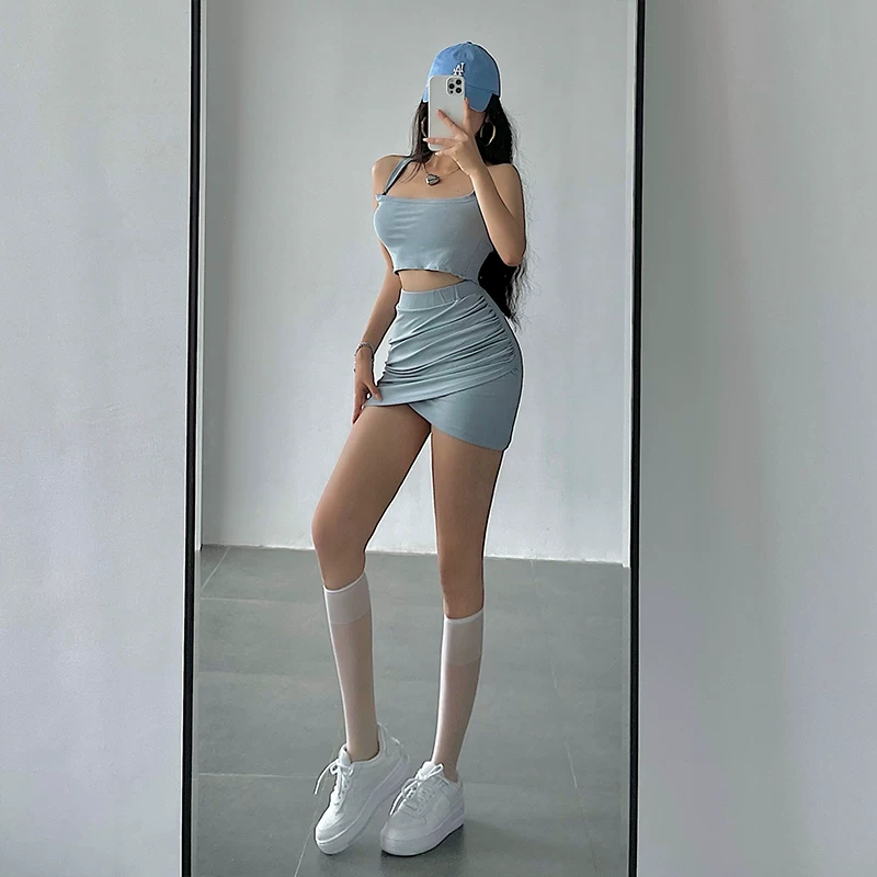 Bộ trang phục gồm áo crop top ôm sát cổ halter và chân váy xếp ly ôm sát eo cao dành cho nữ.