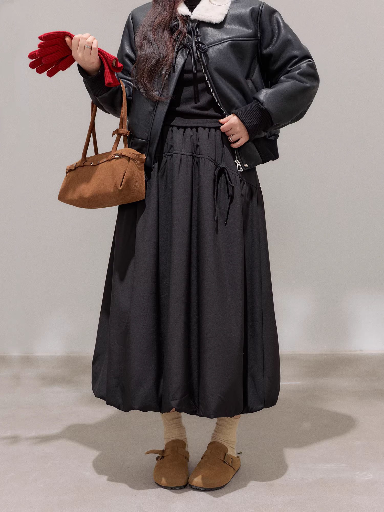 Bộ trang phục mùa đông cho nữ cỡ lớn: Áo khoác da đen tôn dáng với cổ lông trắng và bộ chân váy hoa lưng cao.