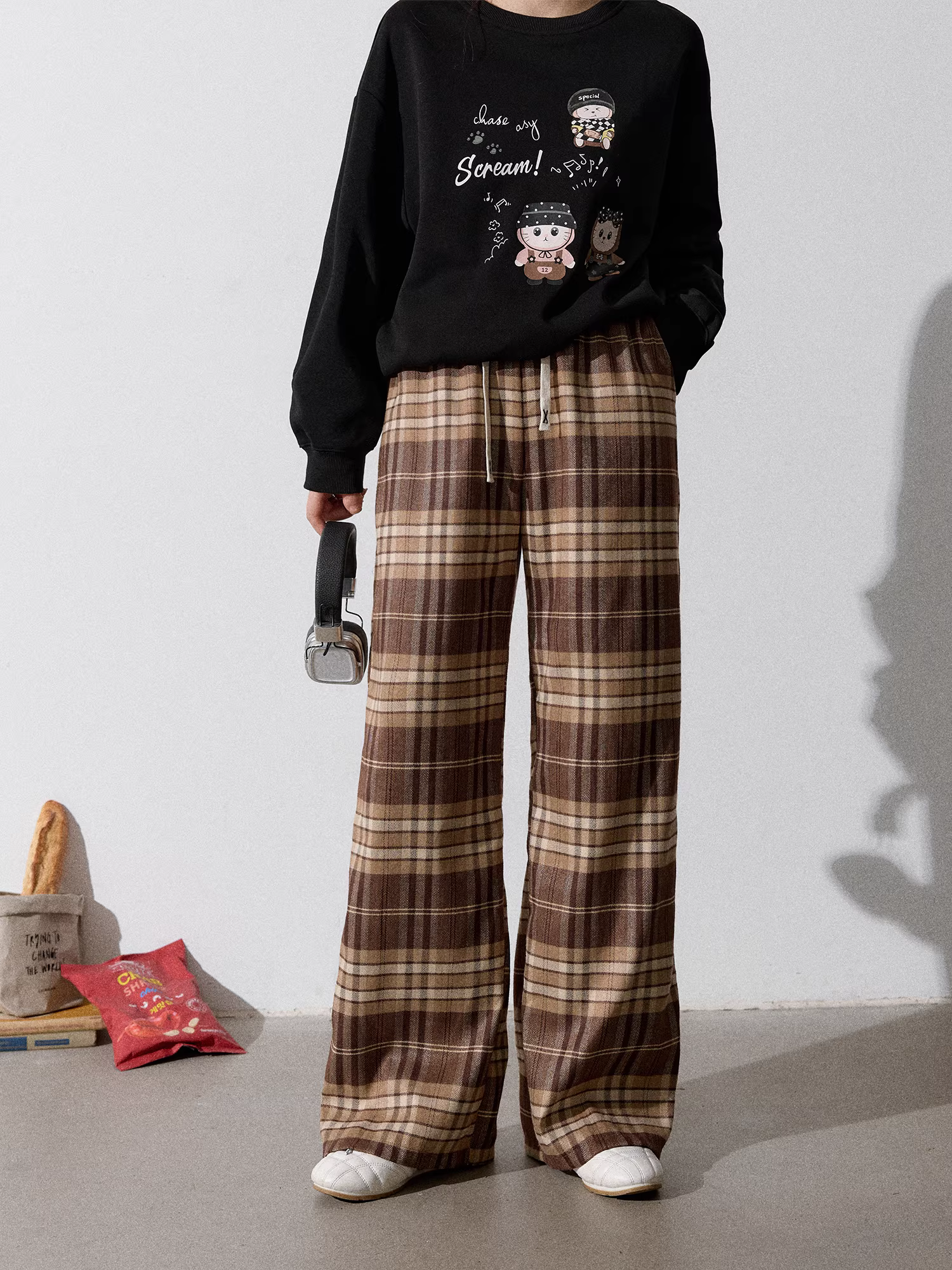 Quần áo nữ cỡ lớn dành cho người lớn, bộ áo nỉ đen cổ tròn kiểu dáng thu mới giúp thon gọn và quần kẻ sọc nâu.