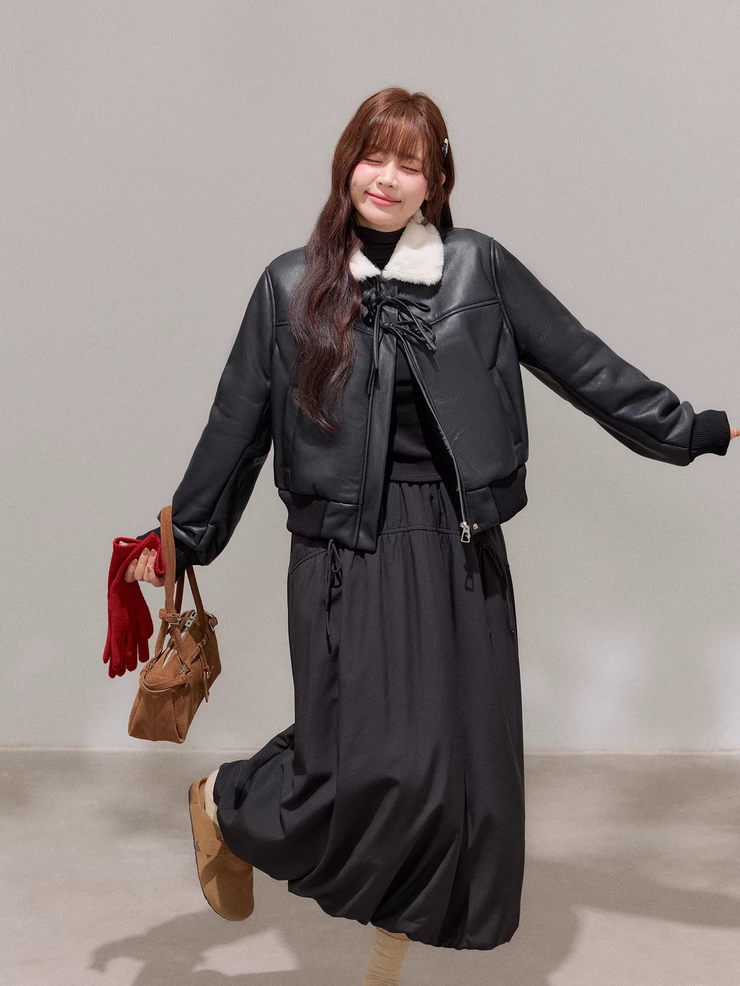 Bộ trang phục mùa đông cho nữ cỡ lớn: Áo khoác da đen tôn dáng với cổ lông trắng và bộ chân váy hoa lưng cao.