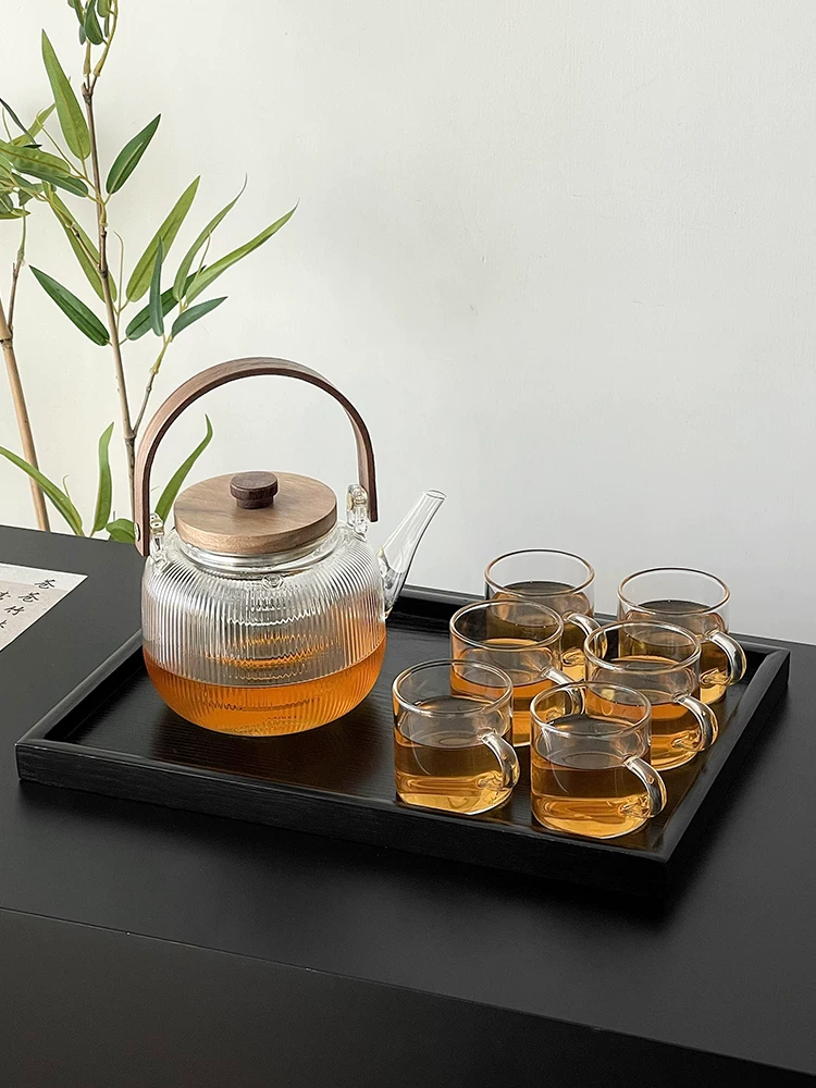 Bộ dụng cụ pha trà với ấm trà bằng thủy tinh chịu nhiệt cao, chén trà và bếp trà bằng gốm.