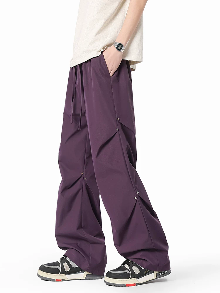 Quần dù xếp ly đính đinh tán Jeanswest dành cho nam, quần ống rộng dáng suông phong cách Mỹ mùa xuân.