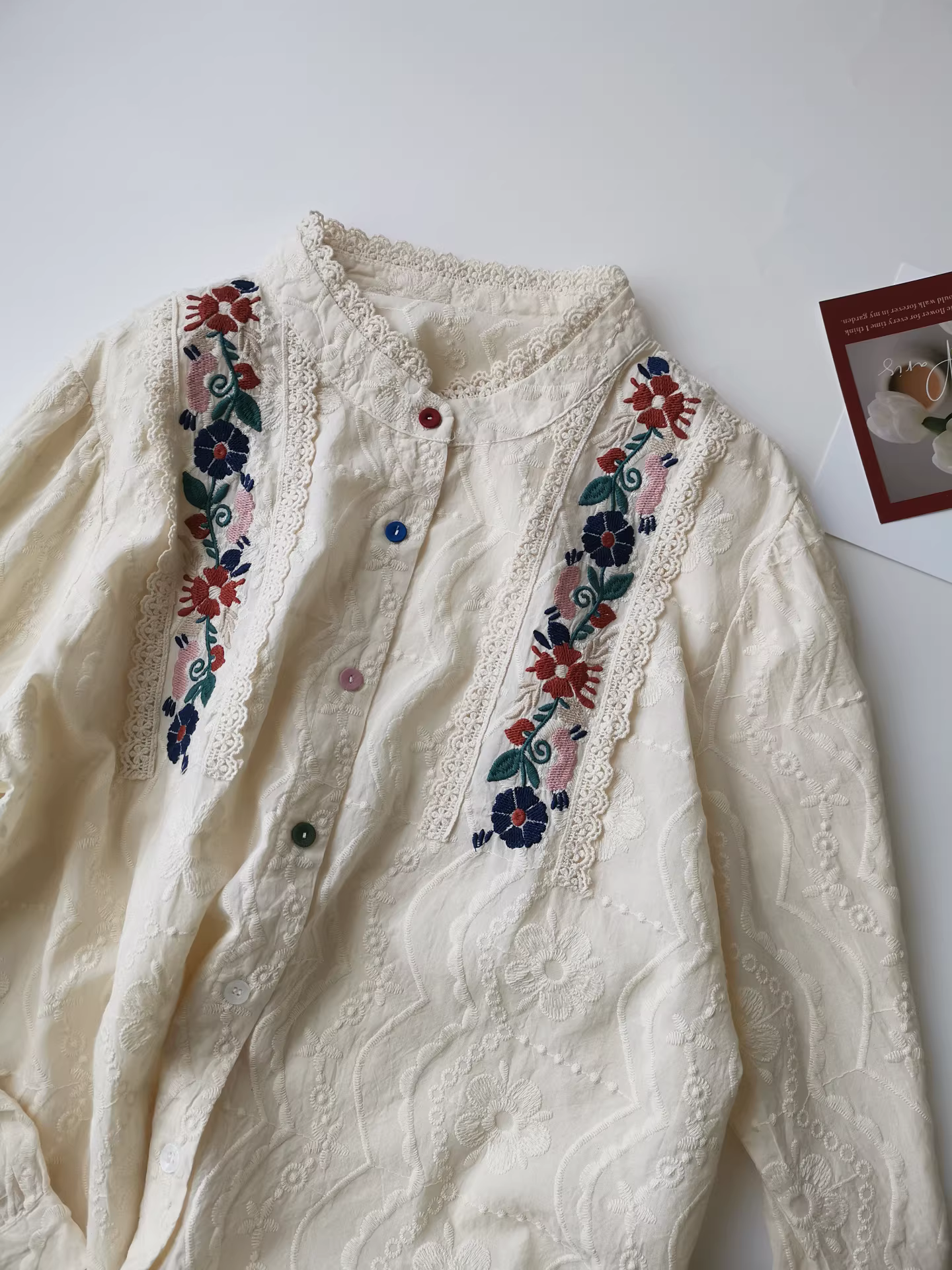 Áo sơ mi màu be thêu họa tiết hoa nhỏ, chất liệu cotton nguyên chất, tay dài, kiểu dáng đa năng và tinh tế.