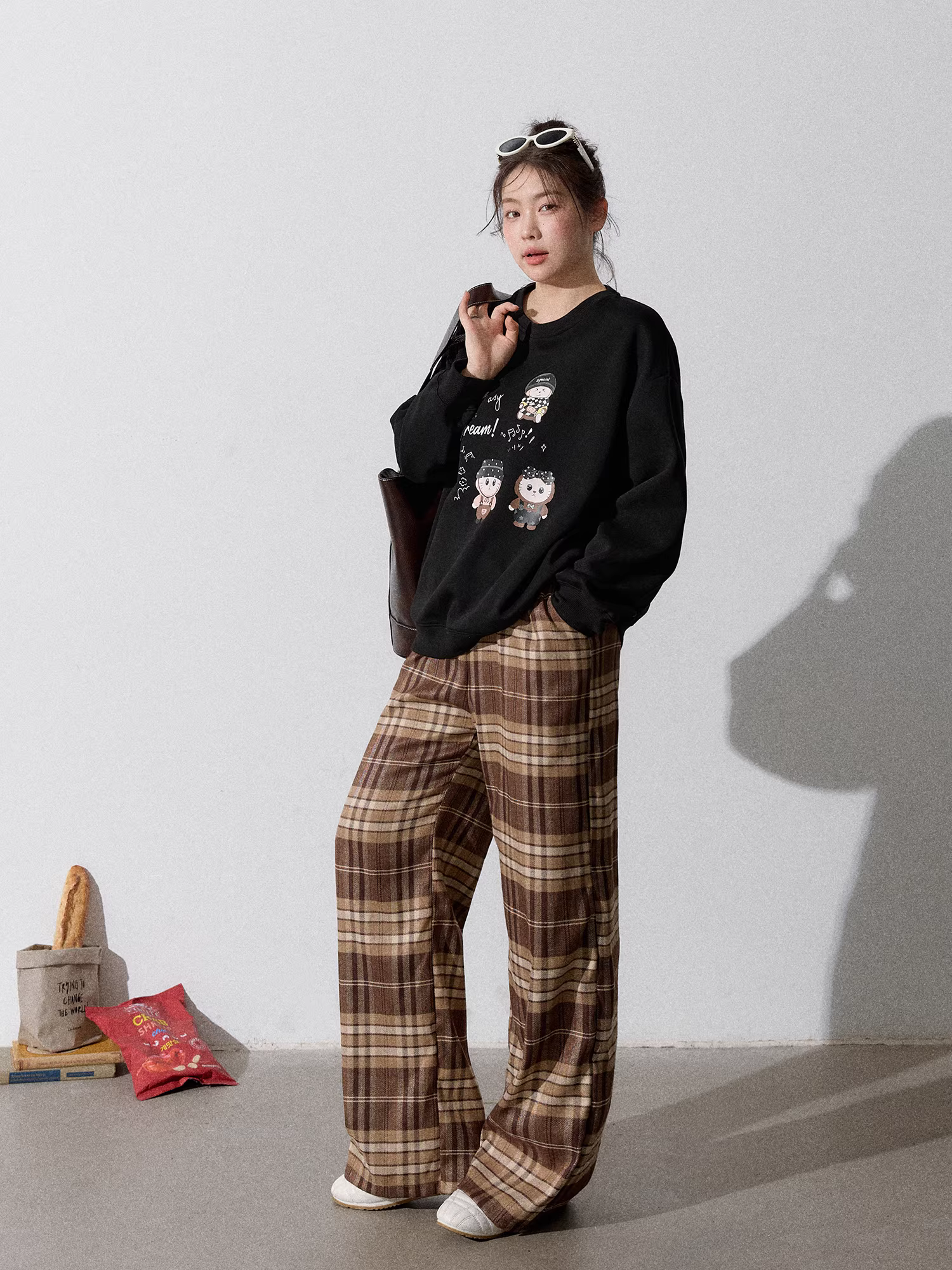 Quần áo nữ cỡ lớn dành cho người lớn, bộ áo nỉ đen cổ tròn kiểu dáng thu mới giúp thon gọn và quần kẻ sọc nâu.