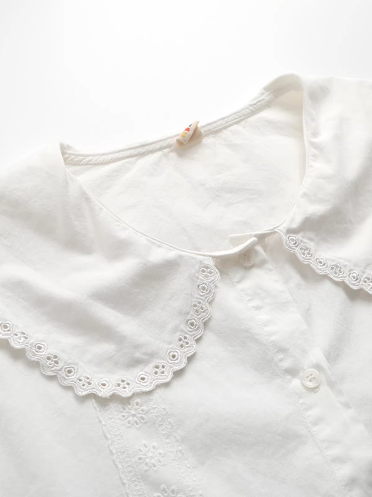 Áo sơ mi cotton phối ren thêu rỗng cổ búp bê dáng rộng màu trắng Dream Box Xuân 2025